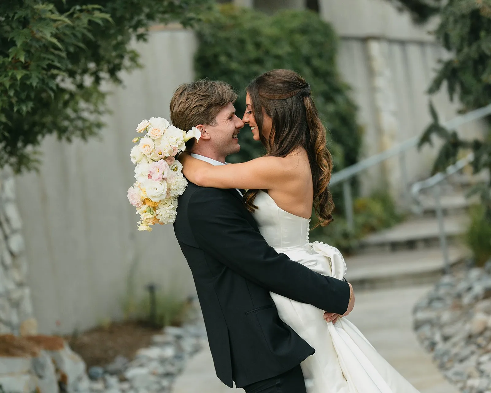 Bride holding a soft blush, pale yellow, peach, and white summer bouquet