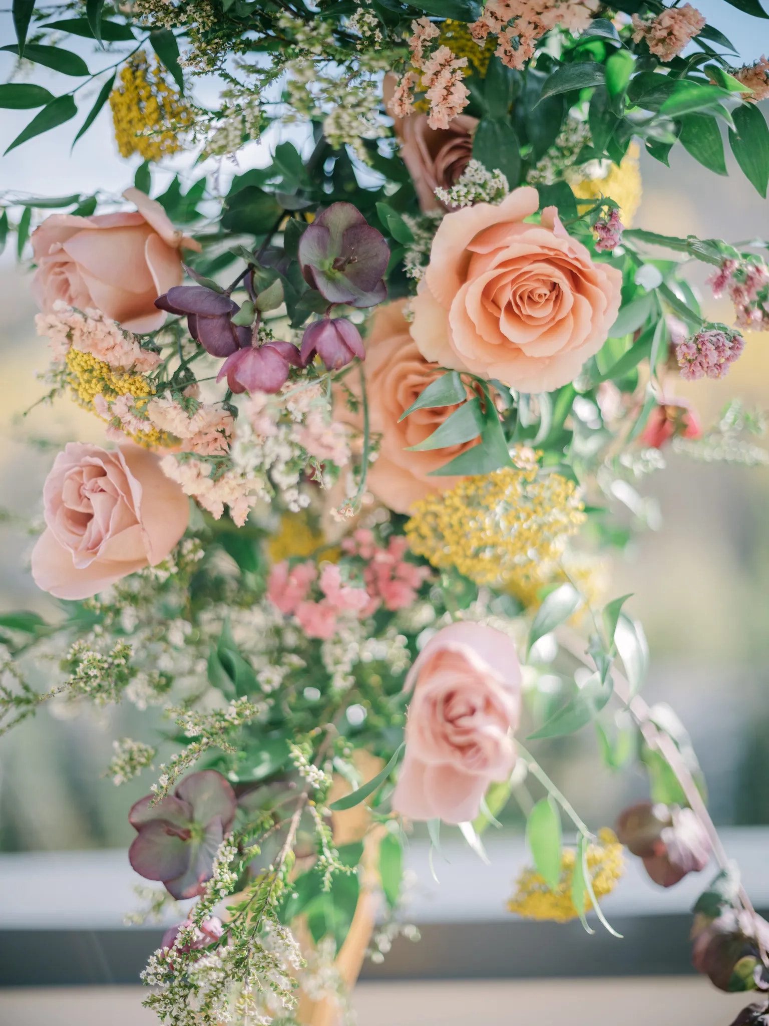 Close-up of peach roses, mauve blooms, yellow accents, and greenery in a fall floral installation at The Hythe Vail