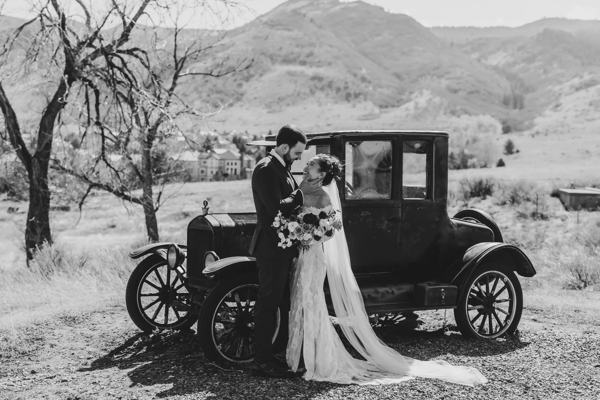 Bride and groom by a vintage car with the Ken Caryl Valley foothills behind at The Manor House in Littleton, Colorado