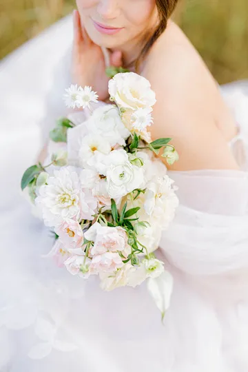 Bride in off-shoulder gown holding a white and blush garden bouquet