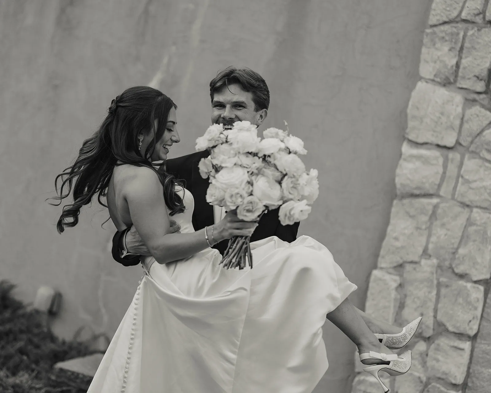 Newlywed couple with a white floral bouquet in a black-and-white portrait