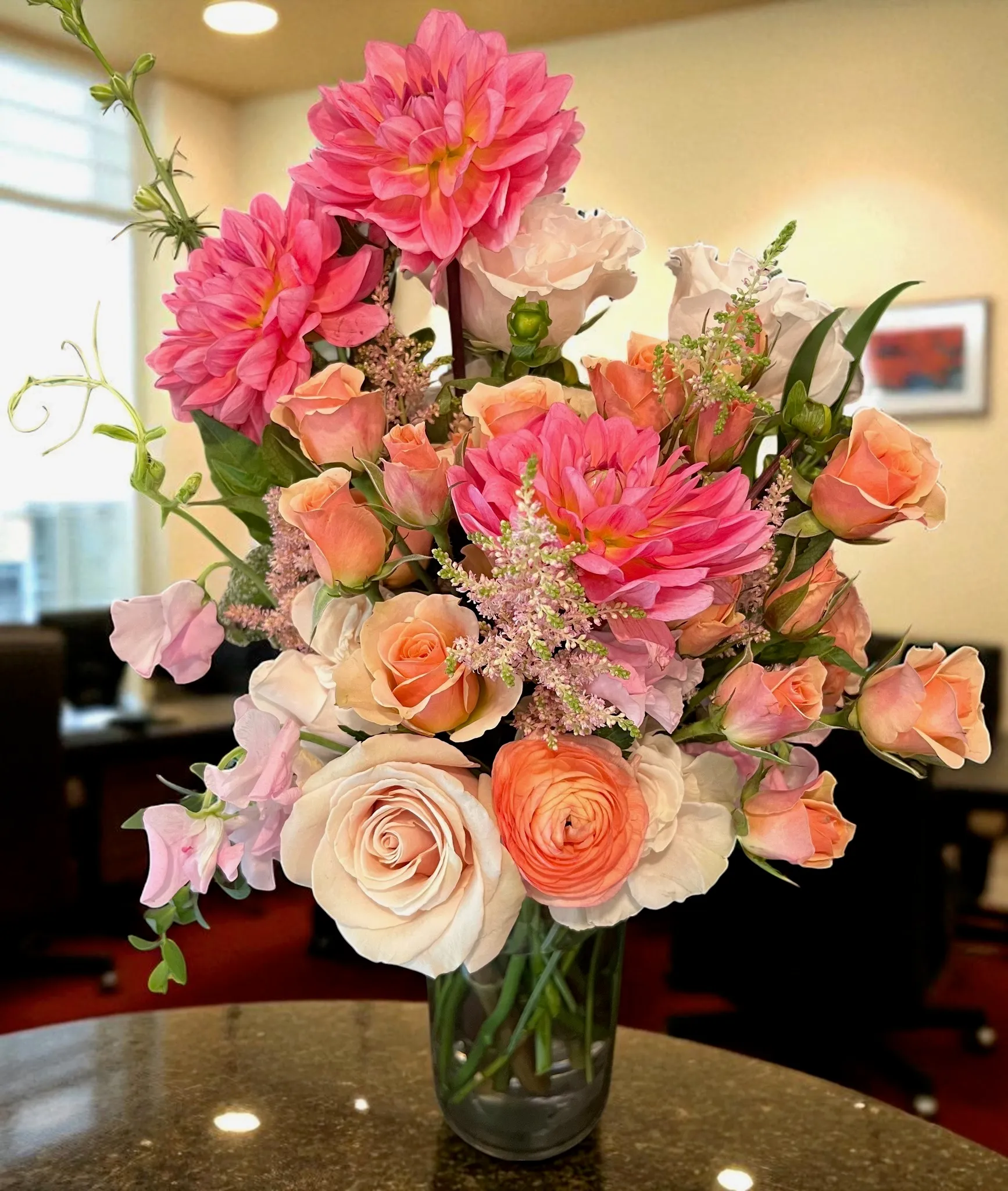 Coral, pink, and blush flowers arranged in a glass vase