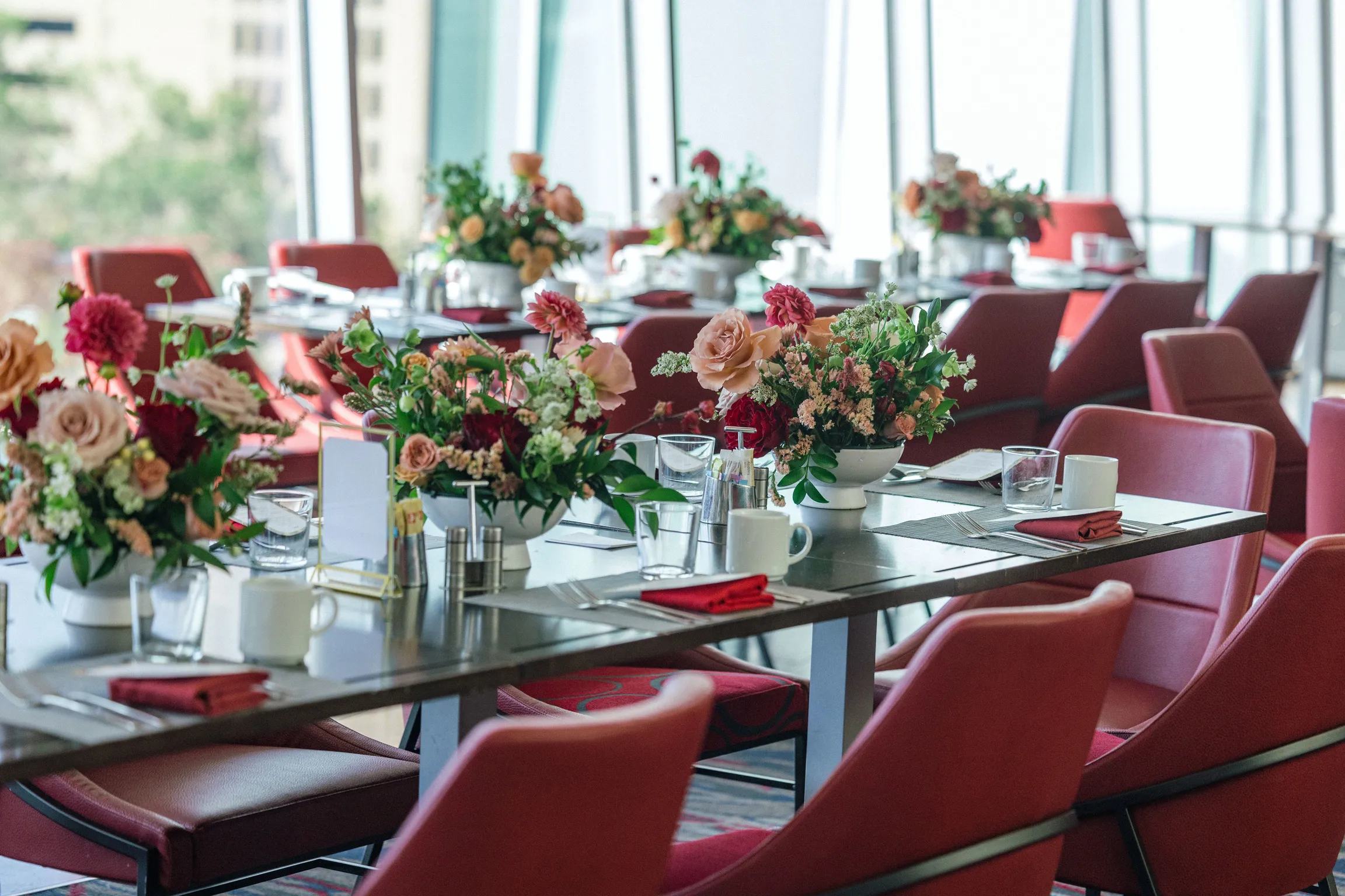 Corporate dining tables with colorful floral centerpieces and red seating