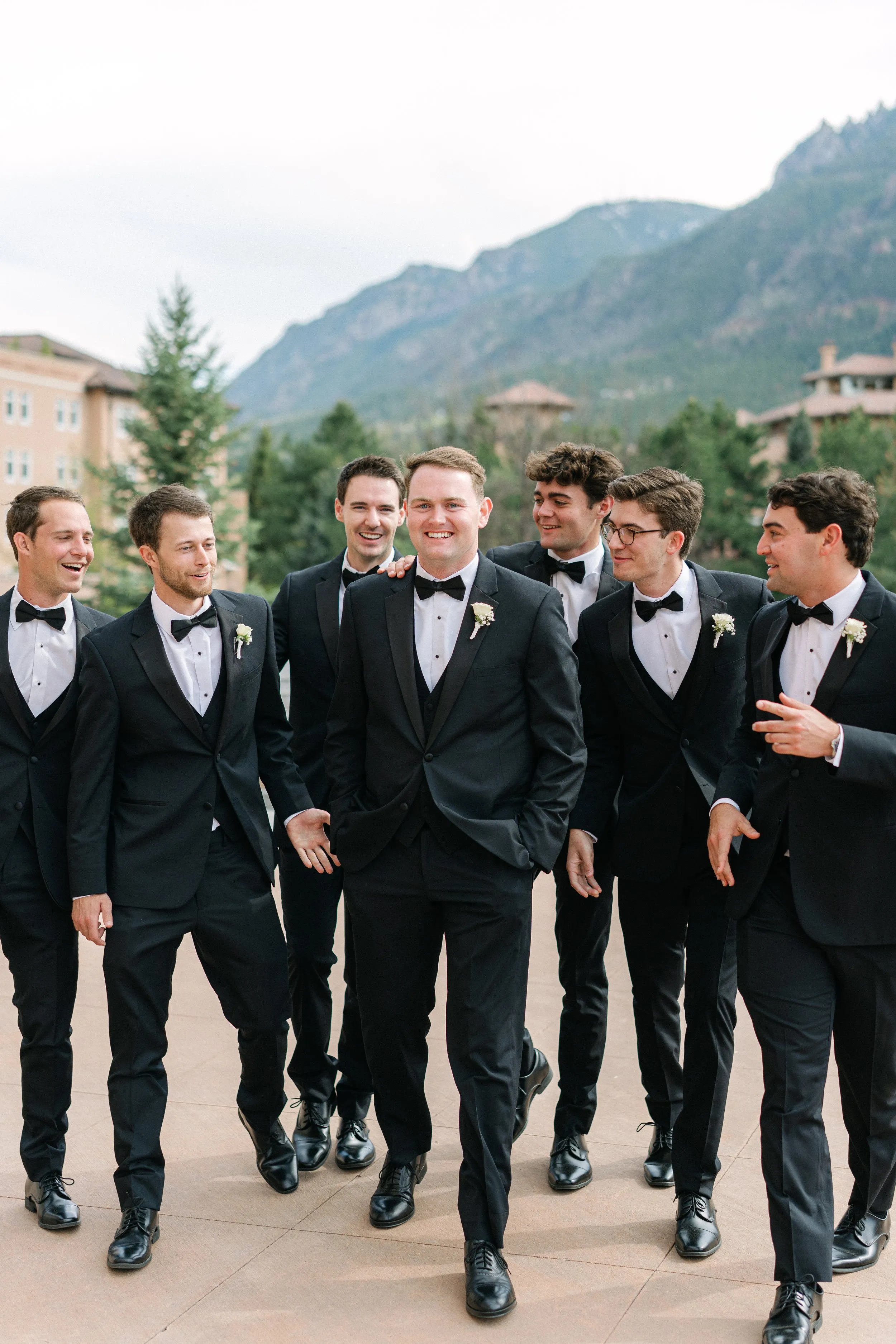 Wedding groomsmen in tuxedos with outdoor mountain backdrop