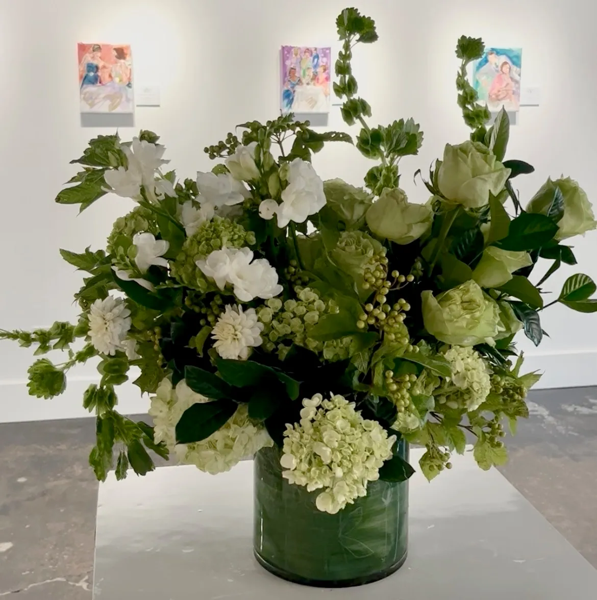 Green and white flowers arranged in a glass cylinder