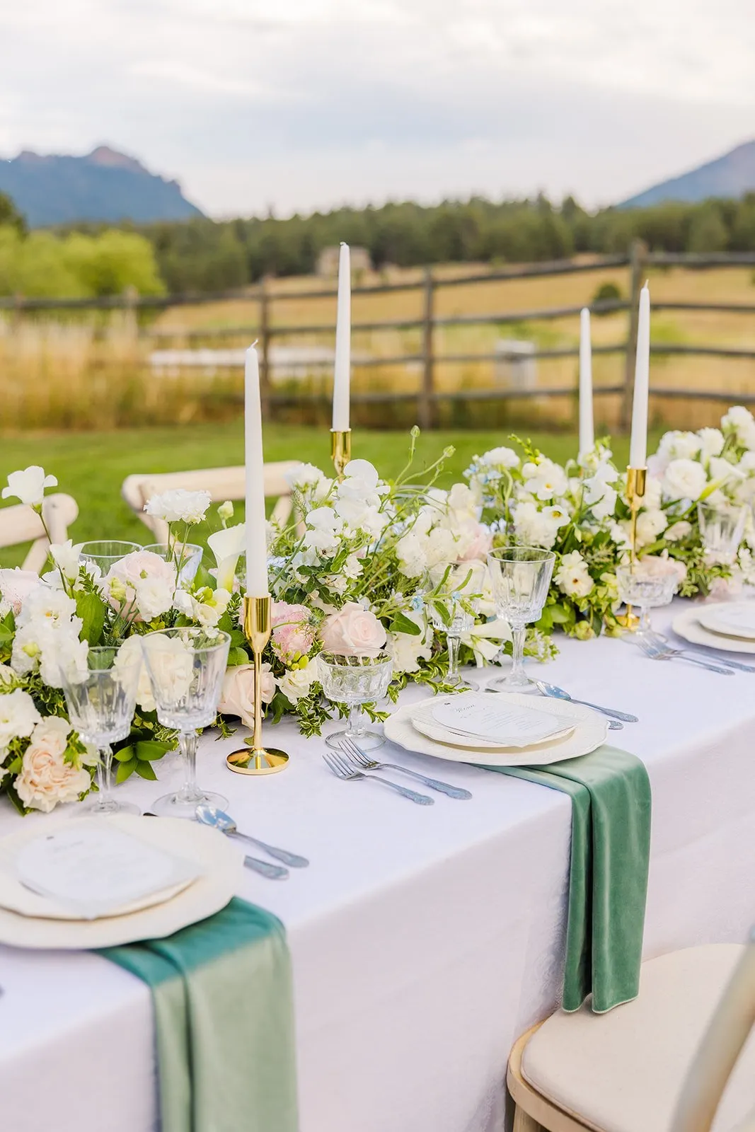Outdoor wedding table with pink and white florals, candles, and mountain view