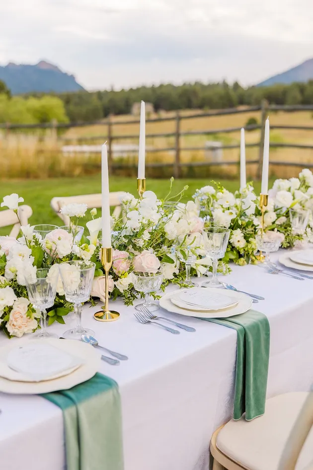 Outdoor wedding table with pink and white florals, candles, and mountain view