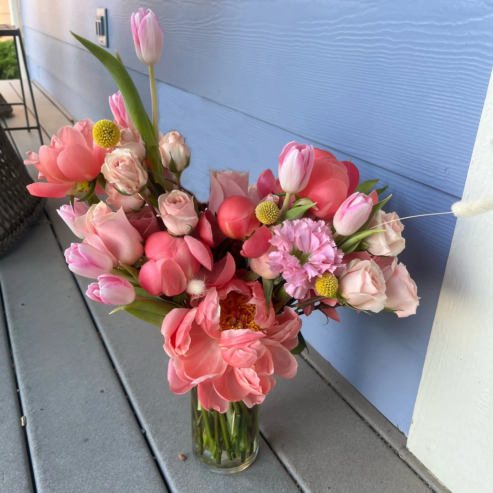 Pink tulips, peonies, and roses in a glass vase