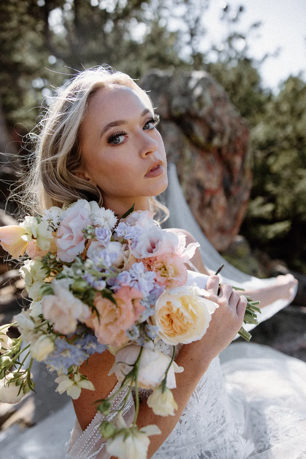 Bride holding a pastel bouquet against a mountain backdrop